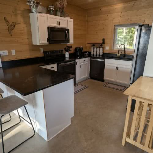 हमारे पूरी तरह से सुसज्जित रसोईघर में अंतर्निहित प्रकाश व्यवस्था और आधुनिक अलमारियां हैं, जो झील के किनारे स्थित घर में खाना पकाने के लिए एक उज्ज्वल और आकर्षक स्थान बनाती हैं।